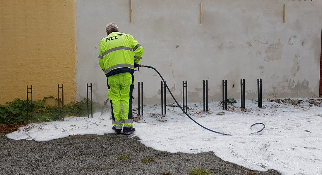 Medarbejder spreder et tyndt lag hvidt skum ud på en cykelparkeringsplads for at bekæmpe ukrudt
